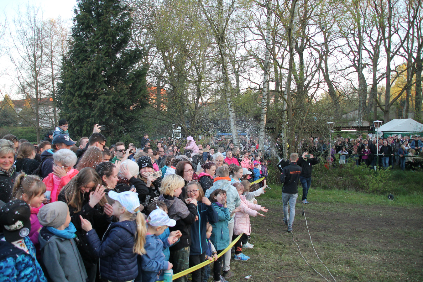 Große Menschenmenge klatscht bei einem Freiluft-Event im Park.