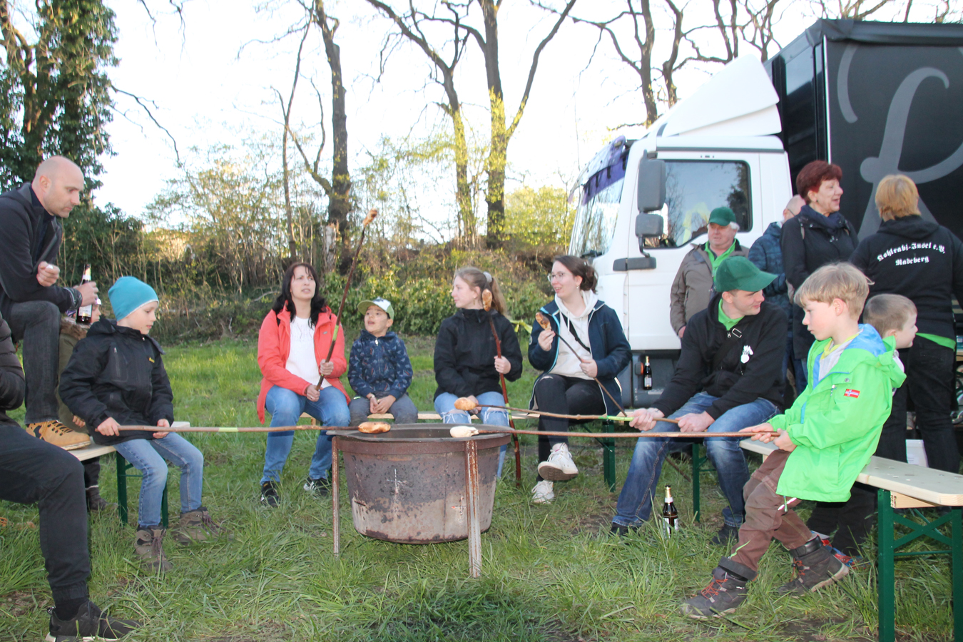 Gruppen am Lagerfeuer mit gegrilltem Essen in freier Natur.